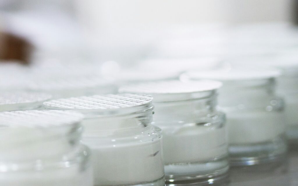 Glass jars filled with white cream, illustrating lanolin in pharmaceutical formulations.
