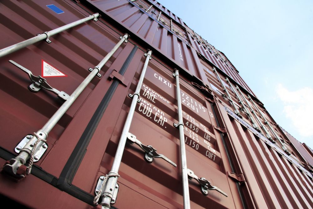 Stacked shipping containers, illustrating international logistics and lanolin supply chains.